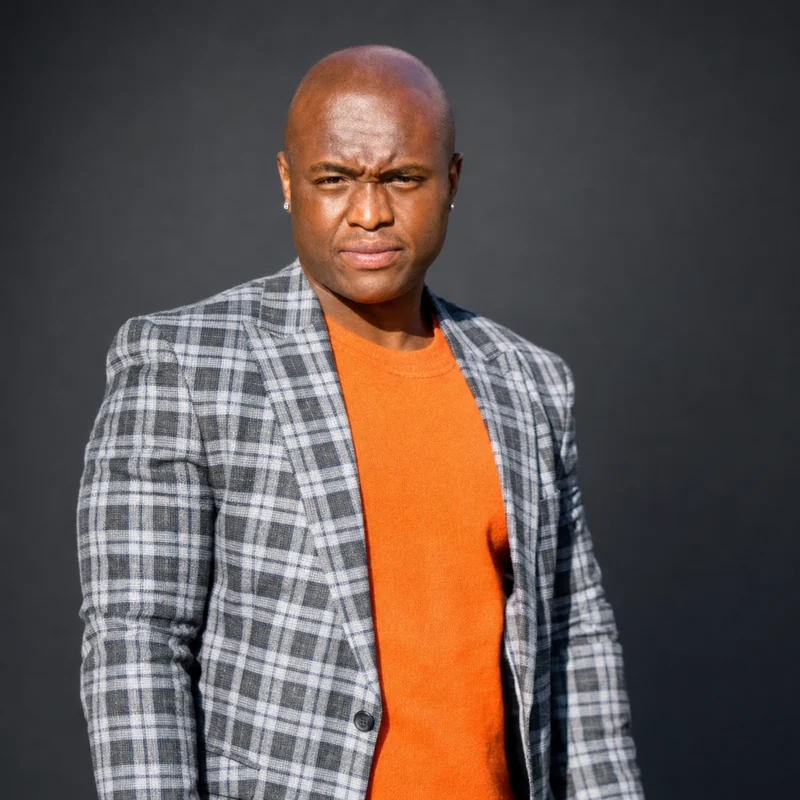 Mtuthuko Mngomezulu in an orange sweater and grey plaid blazer